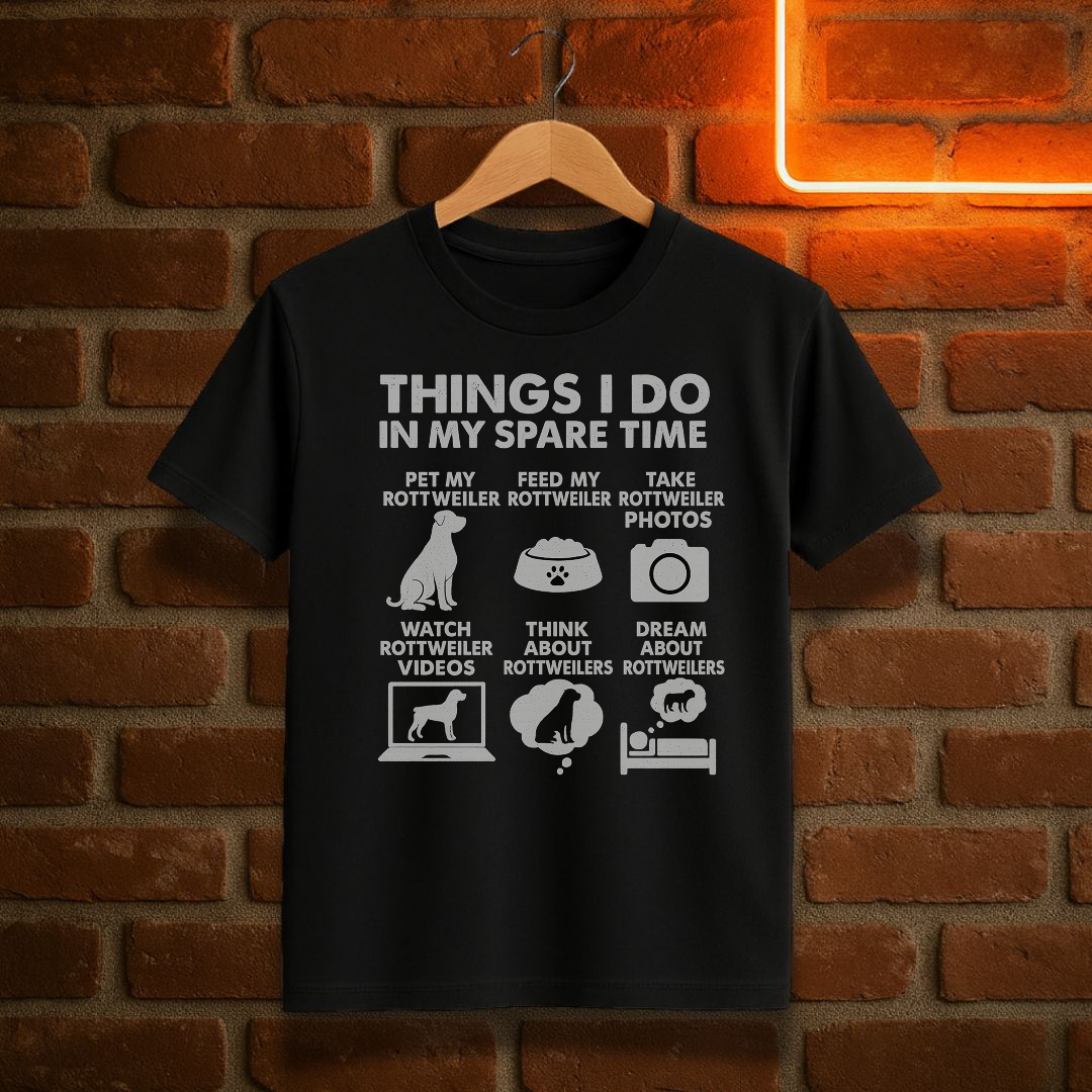 Black t-shirt with white text and graphics on a hanger against a brick wall background