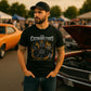Man wearing a black t-shirt with 'Catburetors' design at a car show.