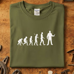 Evolution of Man mekaniker t-skjorte med trykk av menneskelig utvikling i hvitt på olivengrønn bakgrunn.