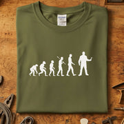 Evolution of Man mekaniker t-skjorte med trykk av menneskelig utvikling i hvitt på olivengrønn bakgrunn.