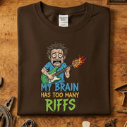 My Brain Has Too Many Riffs T-Skjorte med grafisk design av en spiller på brunt stoff, perfekt for musikkelskere.
